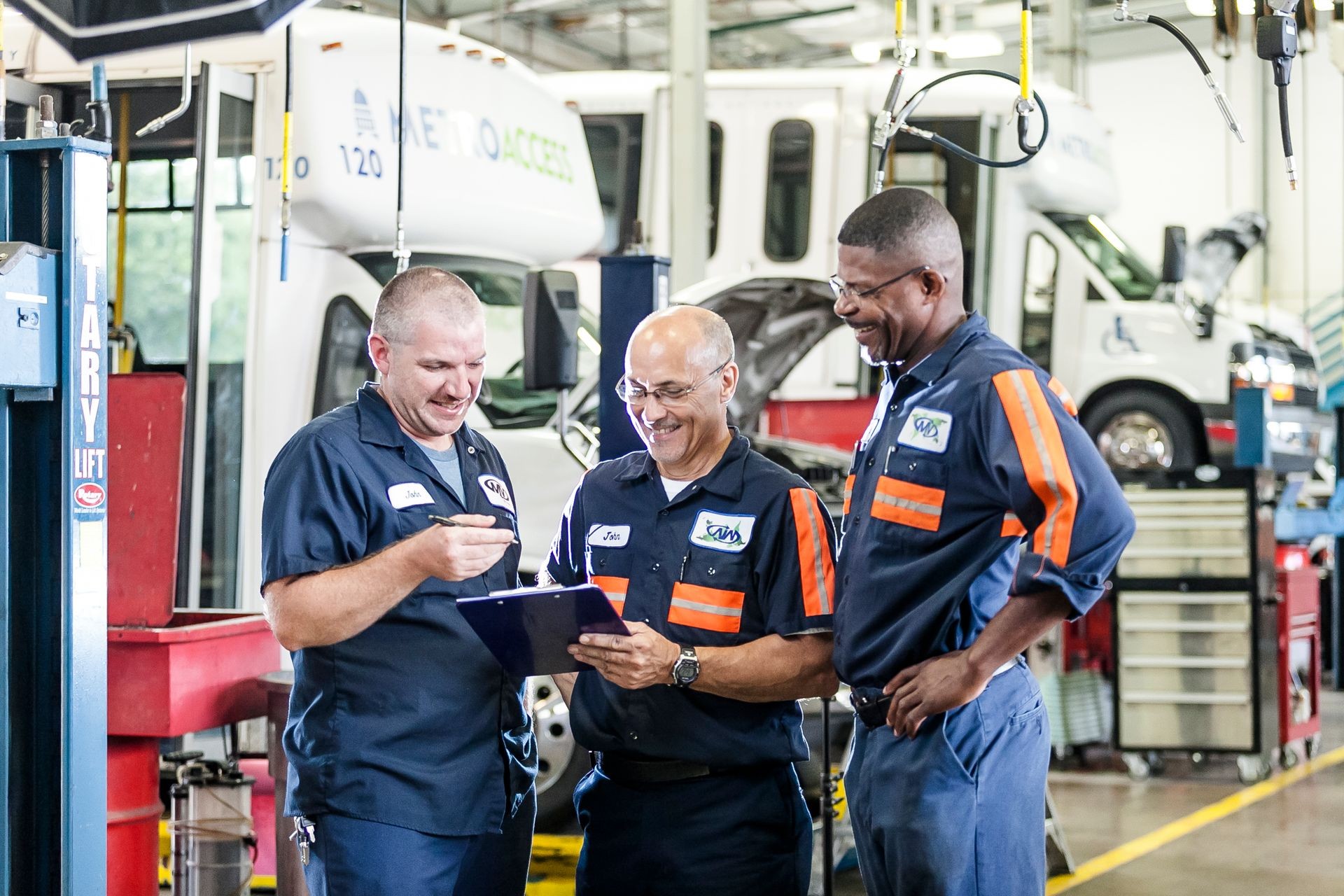 Three workers standing in front of a paratransit bus