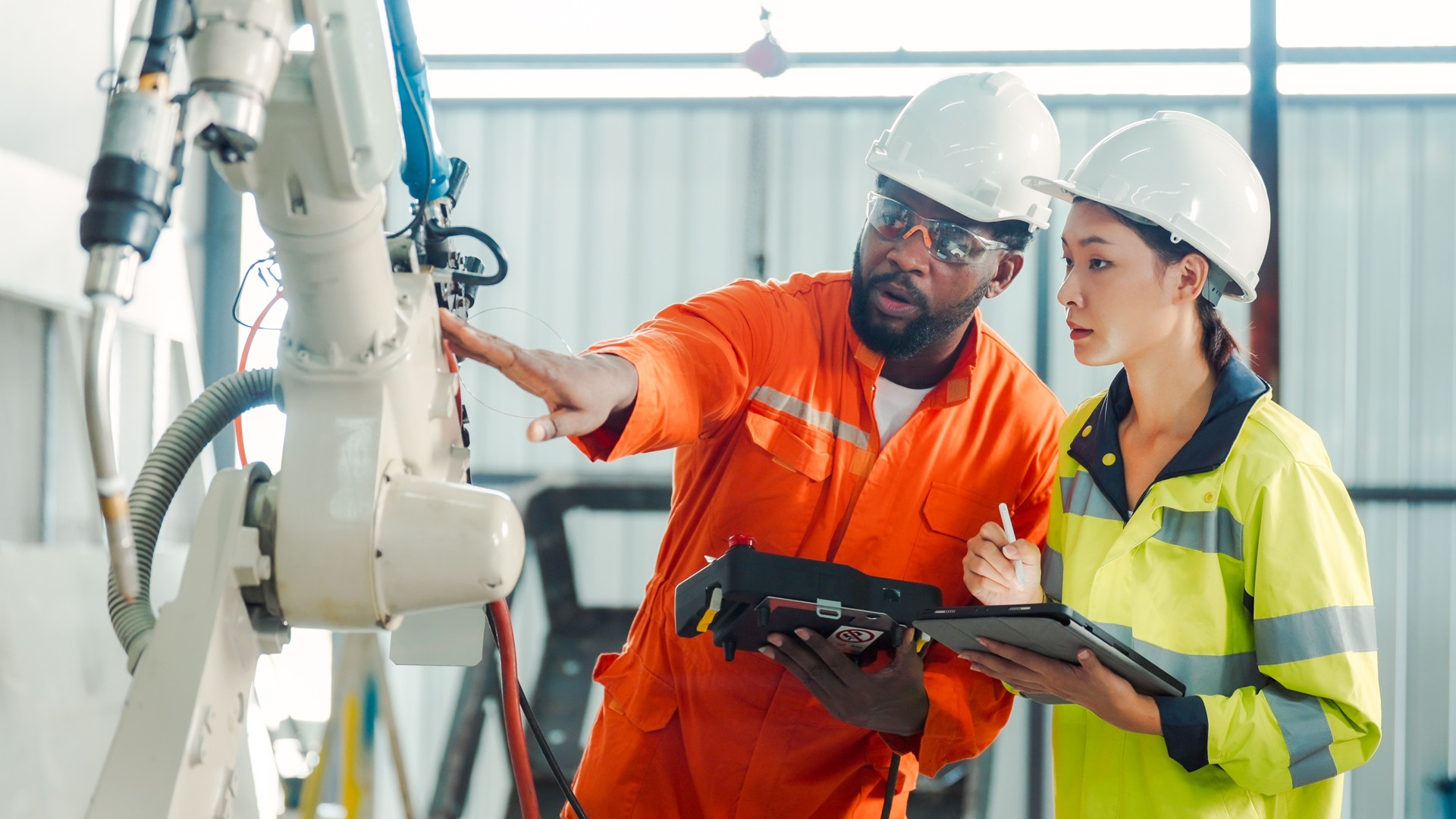 2 workers in hardhats examining machinery and discussing