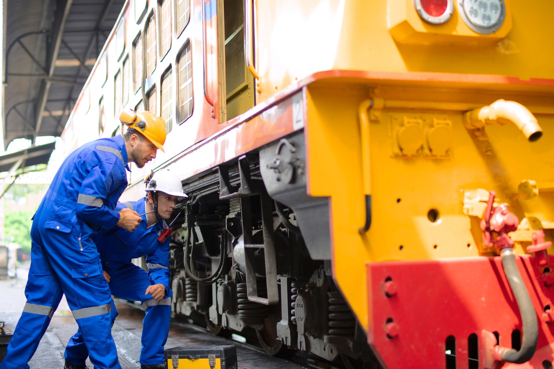 Blue collar workers are working at train garage.