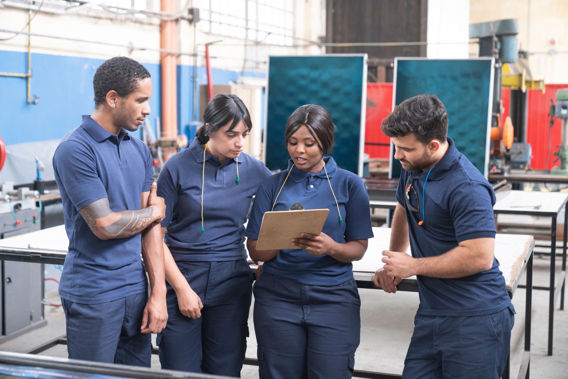African-american female supervisor showing planning to workers from a clipboard at solar panel factory