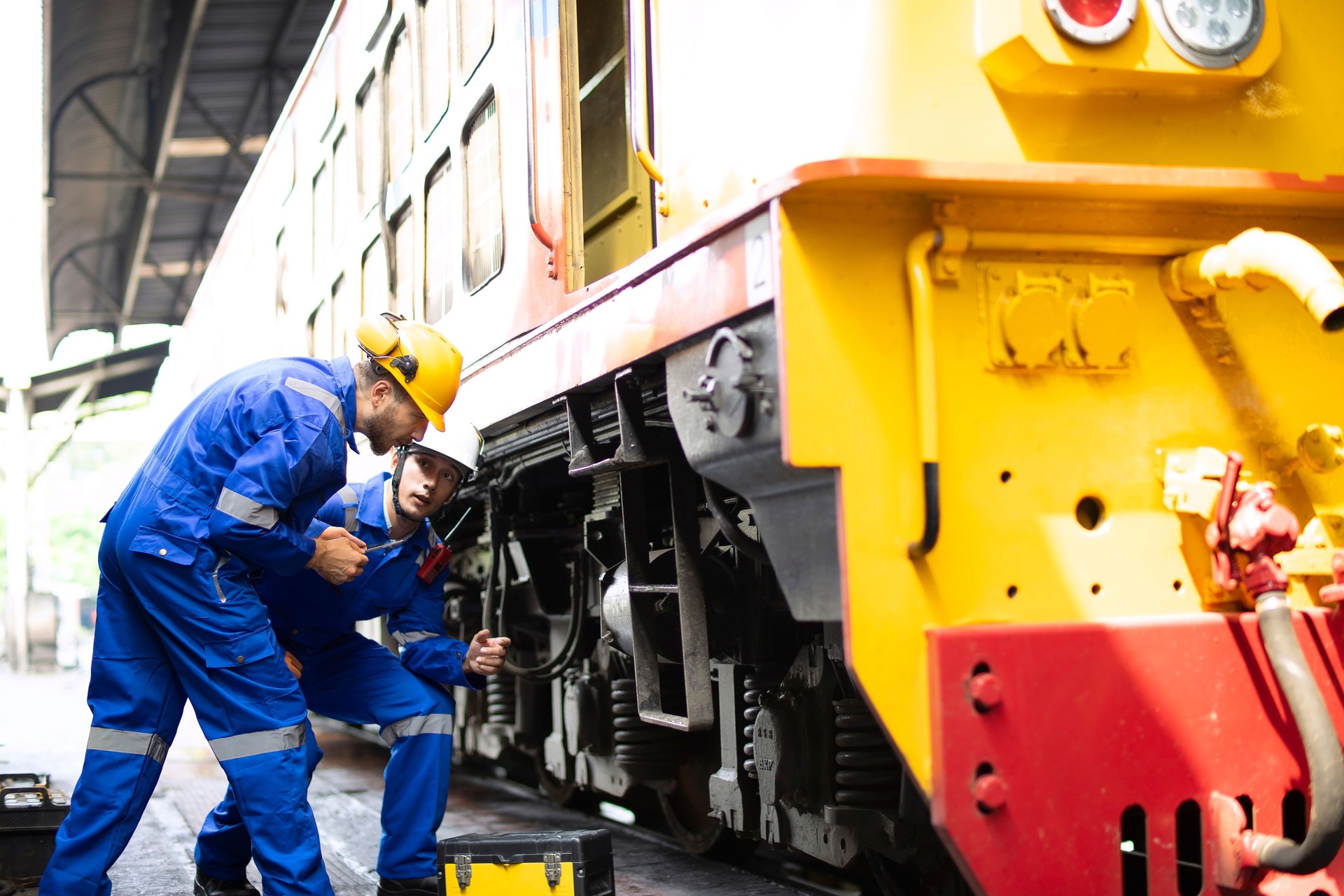 Blue collar workers are working at train garage.
